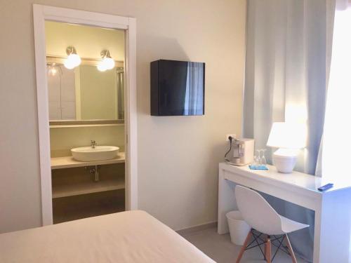 a bathroom with a sink and a desk with a chair at ESMERALDA'S ROOMS in Porto San Paolo