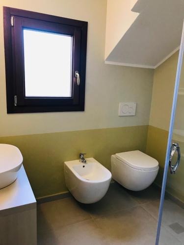 a bathroom with a sink and a toilet and a window at ESMERALDA'S ROOMS in Porto San Paolo
