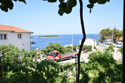 a red truck parked in a parking lot next to the ocean at Apartments and Room Mate-Mare in Primošten