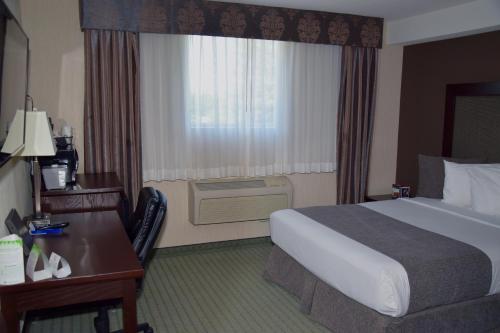 a hotel room with a bed and a desk and a window at Coast Lethbridge Hotel & Conference Centre in Lethbridge