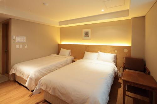 a hotel room with two beds and a chair at Dream House in Seoul