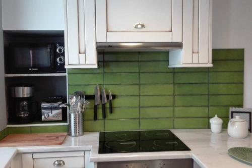 a kitchen with white cabinets and green tile on the wall at Azoka by the Sea- Centro Histórico de Peniche in Peniche