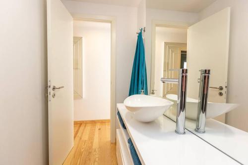 a white bathroom with two sinks and a mirror at Cascais Seaside Duplex - 200m from the beach! in Cascais