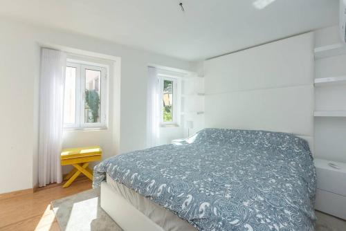 a white bedroom with a bed and two windows at Cascais Seaside Duplex - 200m from the beach! in Cascais