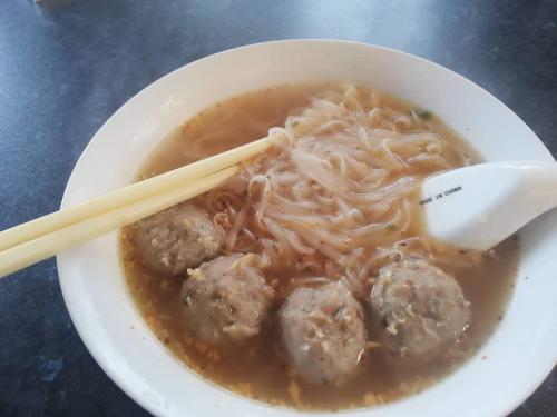 a bowl of soup with meatballs and noodles with chopsticks at rooms with a view in Haywards