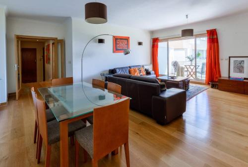 a living room with a glass table and a couch at Fantastic Seaside Family Apartment with Pool in Parede
