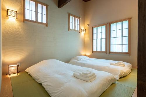 2 camas blancas en una habitación con ventanas en Tsukinoki en Niseko