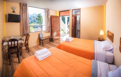 a hotel room with two beds and a table and a desk at Le Foyer Colca in Yanque