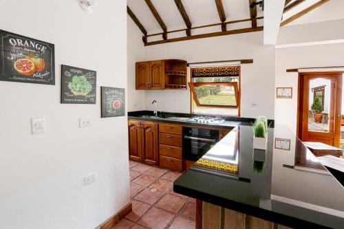 a kitchen with wooden cabinets and a black counter top at Casa de las Flores- Chalet Privado in Villa de Leyva