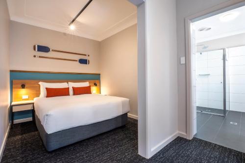 a hotel room with a bed and a shower at Nightcap at Ocean Beach Hotel in Ettalong Beach