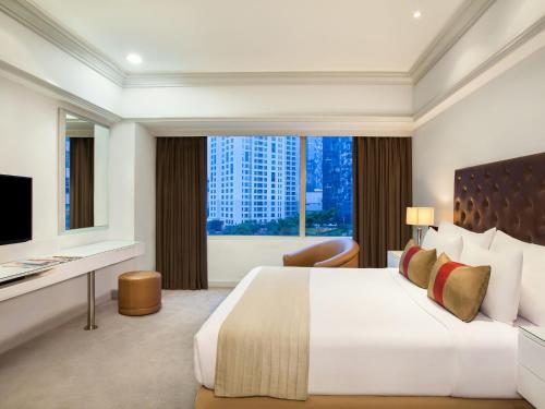 a hotel room with a large bed and a desk at Wyndham Casablanca Jakarta in Jakarta