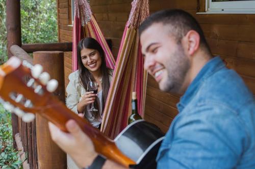 a man playing a guitar while a woman smiles at Cabañas La Silleta in Santa Elena