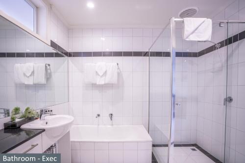 ein weißes Bad mit einem Waschbecken und einer Dusche in der Unterkunft Clocktower Apartment Hotel in Melbourne