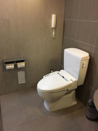 a bathroom with a toilet with a phone on the wall at Citadines Central Shinjuku Tokyo in Tokyo