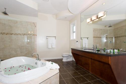 a bathroom with a tub and a toilet and a sink at Shiraz Villa in Osoyoos
