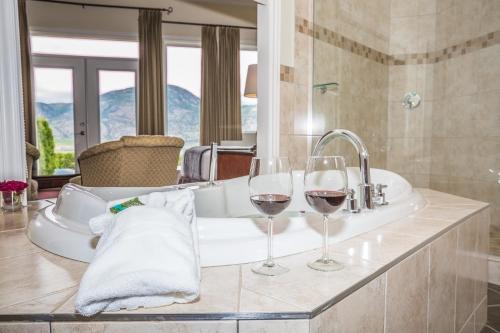 due bicchieri di vino seduti su un lavandino del bagno di Shiraz Villa a Osoyoos