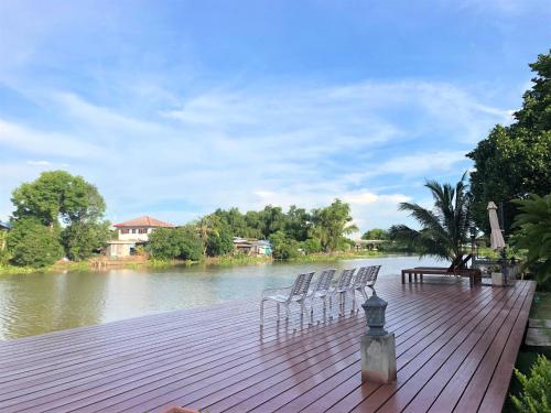 a group of chairs sitting on a wooden deck next to a river at Thararin Villa in Ban Doem Bang (1)