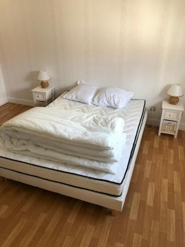 een bed met witte lakens en kussens erop bij Chez Nono et Soso in Eurville