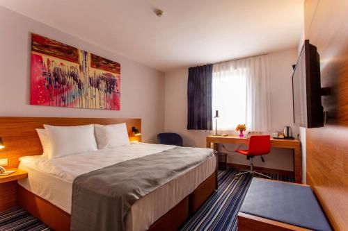 ソフィアにあるソフィア プラザ ホテルのベッド、デスク、テレビが備わるホテルルームです。