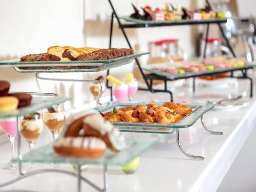 a buffet with several trays of pastries and other foods at Novotel Jazan in Jazan