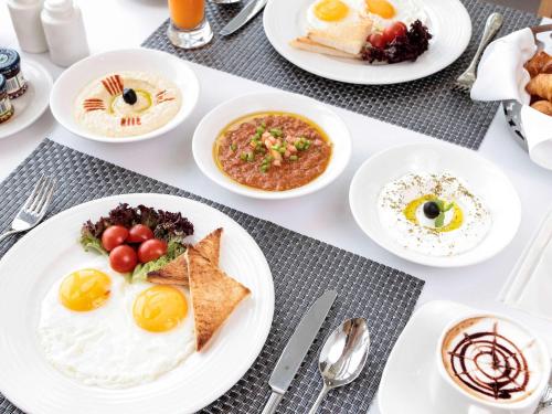 a table with plates of breakfast food on it at Novotel Jazan in Jazan