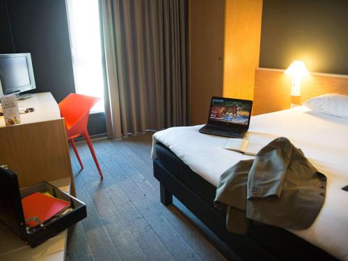 a hotel room with a bed with a laptop on it at Hotel Ibis Firenze Nord Aeroporto in Sesto Fiorentino