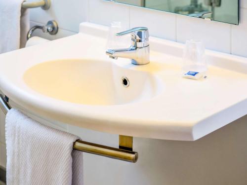a sink in a bathroom with a mirror at ibis budget Pau Lescar in Lescar