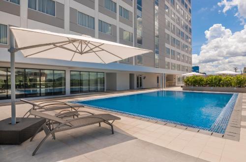 a pool with a chair and an umbrella next to a building at Park Inn By Radisson Iloilo in Iloilo City