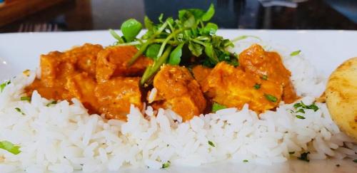 a plate of rice and meat with a side of greens at The Waterfront in Portpatrick