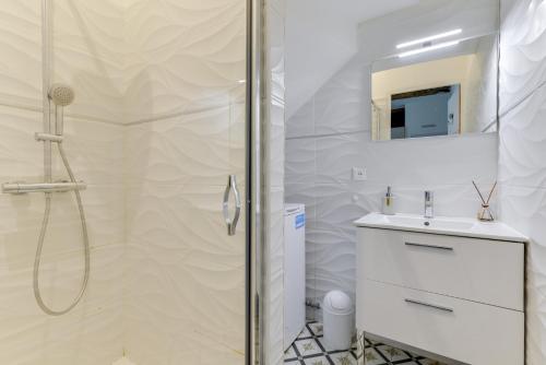 baño blanco con ducha y lavamanos en Votre adresse de charme centre historique de Béziers, en Béziers
