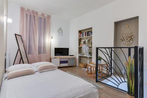 Habitación blanca con cama y TV en Votre adresse de charme centre historique de Béziers, en Béziers