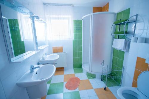 - une salle de bains verte et blanche avec deux lavabos et une douche dans l'établissement Penzion Ajda, à Liptovský Mikuláš