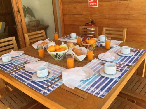 a wooden table with plates and bowls of fruit on it at Hotel Punta Camarón Bungalows & Suites in Zorritos
