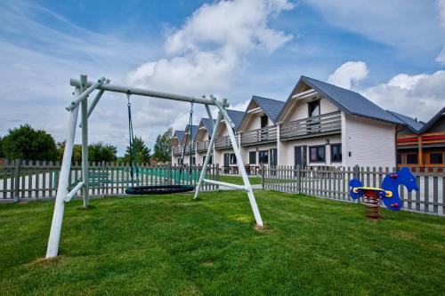 a playground in a yard next to a house at Sarbinowo Prestige - Ekskluzywne domki nad morzem in Sarbinowo