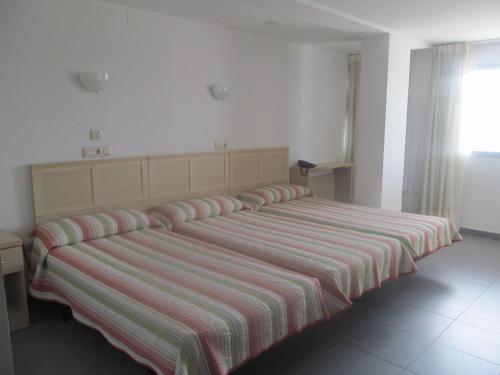 a large bed in a room with a striped blanket at Hotel Cogullada in Zaragoza