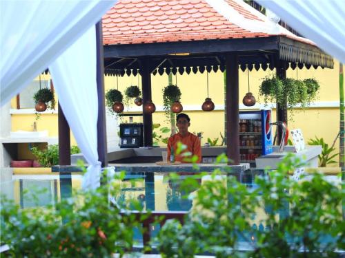 a man sitting at a table in a gazebo at Residence Indochine D'angkor in Siem Reap