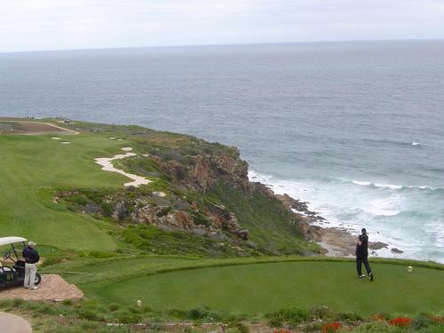 two people standing on a golf course near the ocean at Lodge 90 - Pinnacle Point Estate in Mossel Bay