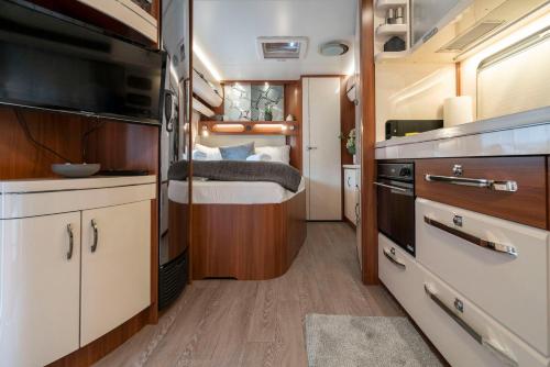 a small kitchen with a bed in a trailer at Bergwelt-M - Scheunencamping in Schröcken