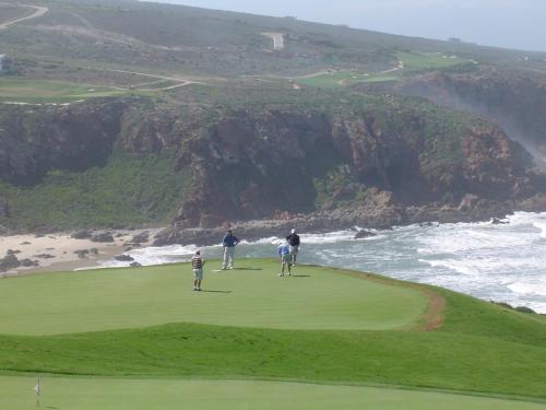three people playing golf on a golf course near the ocean at Lodge 90 - Pinnacle Point Estate in Mossel Bay