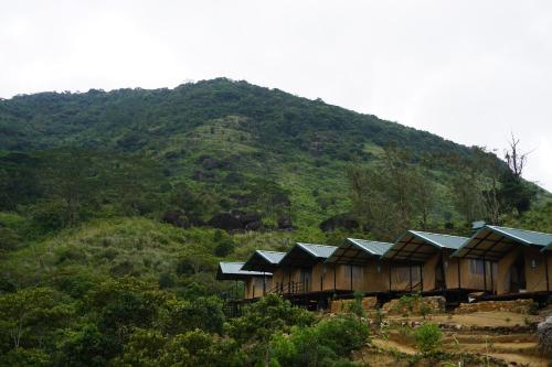 a group of houses on a hill with a mountain at Wild Glamping Knuckles - Thema Collection in Rangala