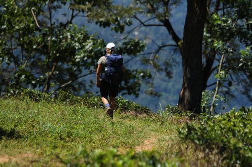 a man walking up a hill with a backpack at Wild Glamping Knuckles - Thema Collection in Rangala