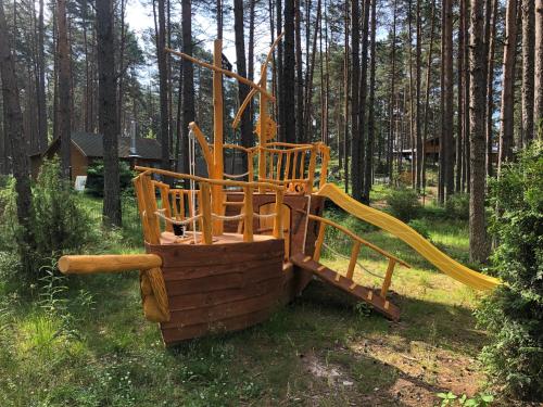 a wooden playground in the middle of a forest at Okka Holiday Home in Alajõe