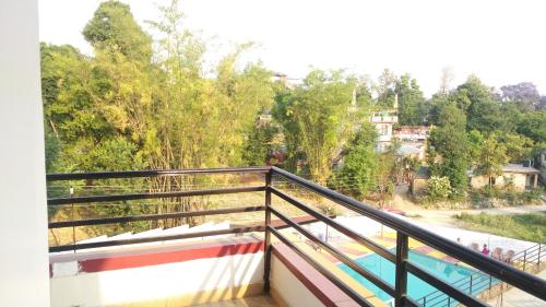 a balcony with a view of a river and trees at Highland Village Resort in Dharmsala