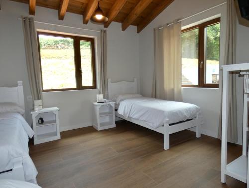 a bedroom with two beds and two windows at Hotel Casa Sueño in Salas