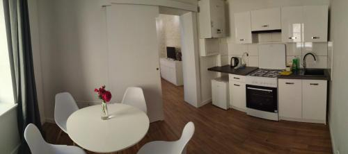 a white kitchen with a table and white chairs at Apartament w starej kamienicy in Mrągowo