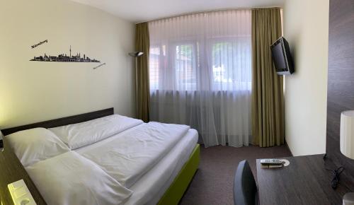 a hotel room with a bed and a television at Behringers City Hotel Nürnberg in Nuremberg
