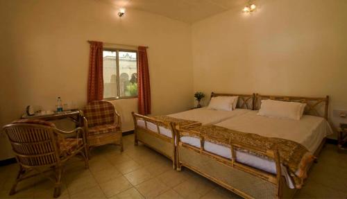 a bedroom with a bed and a chair and a window at KP Cottages in Kānker