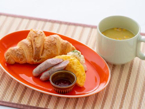 a plate with sausage and bread and a cup of soup at Hotel Waraku Shibukawa in Shibukawa