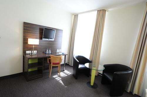 a hotel room with a desk and chairs and a television at Behringers City Hotel Nürnberg in Nuremberg