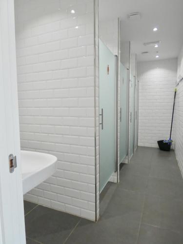 a bathroom with white walls and a sink and stalls at Albergue Casa Sueño in Salas